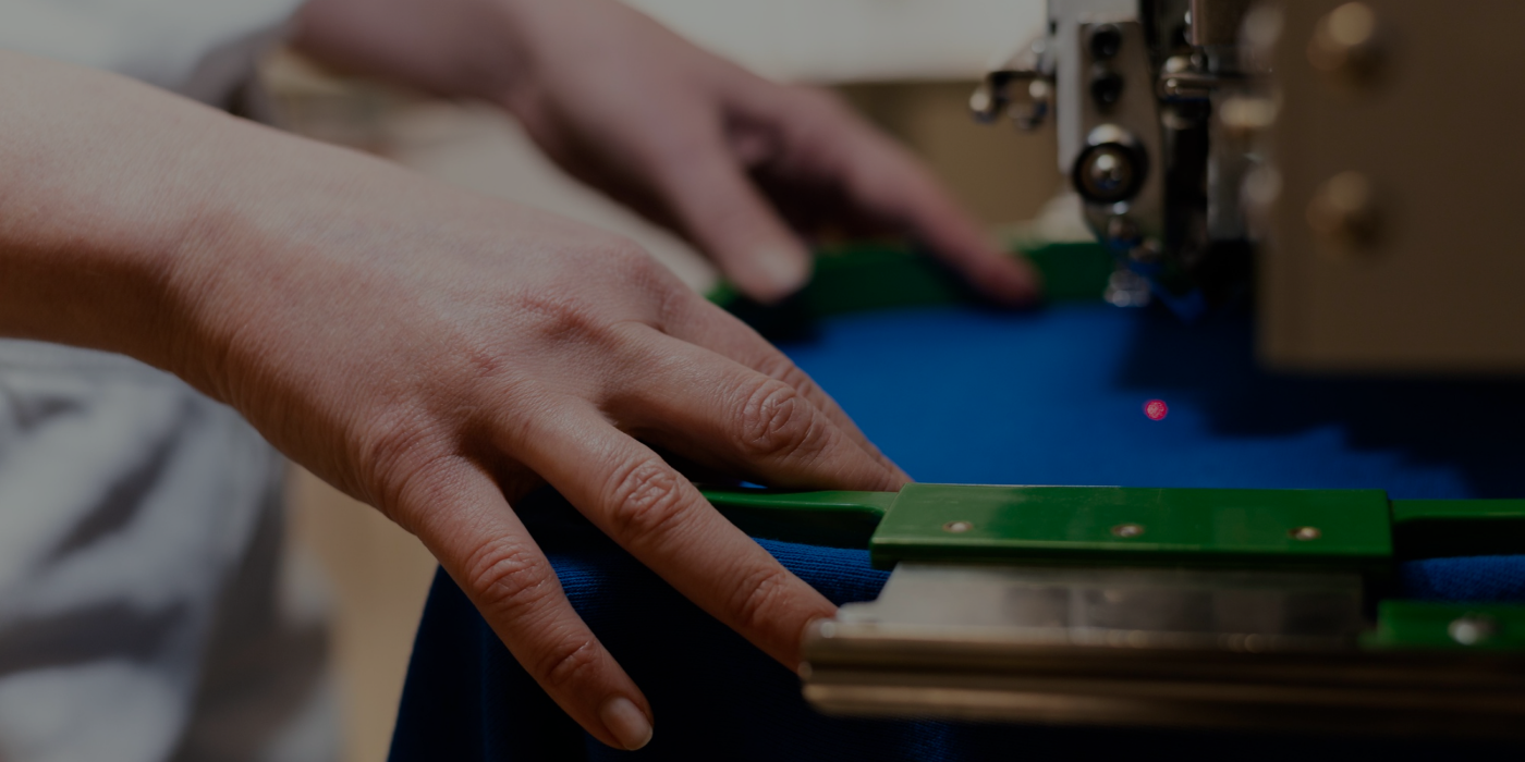 A craftsperson guides fabric through an embroidery machine