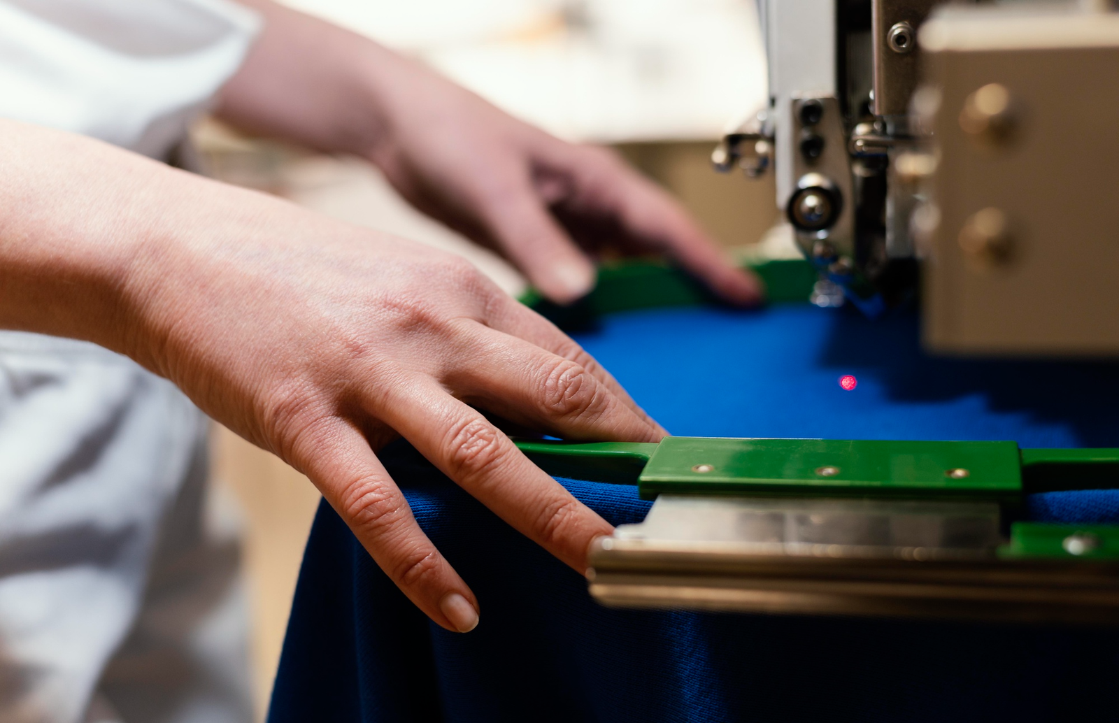 Hands guiding fabric through an embroidery machine